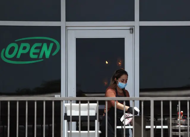 A restaurant employee cleans a outdoor patio table in Texas prior to the scheduled reopening of businesses