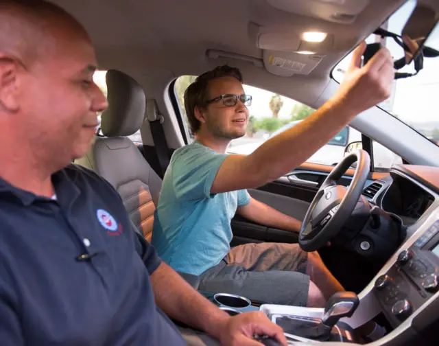 Student driver adjusts mirror