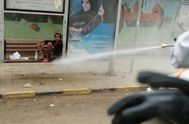 A man looks as a health worker disinfects a street in Sanaa, Yemen. Photo: 28 April 2020