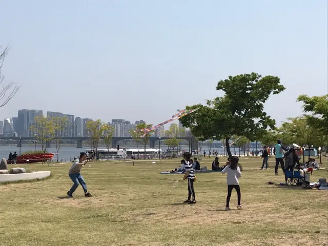 People enjoy the sunshine by the Han River