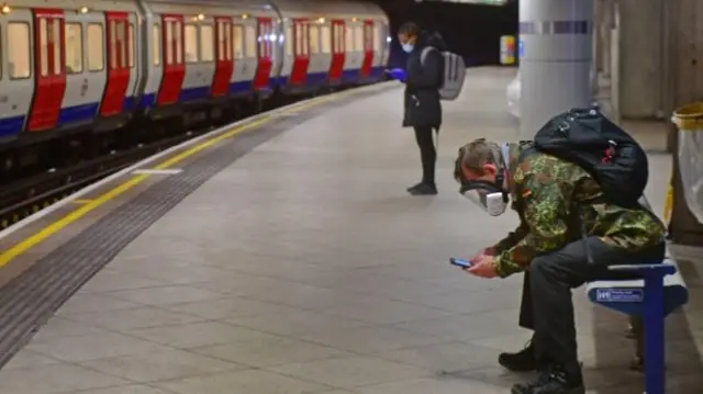 A man in a gas mask at a Tube station