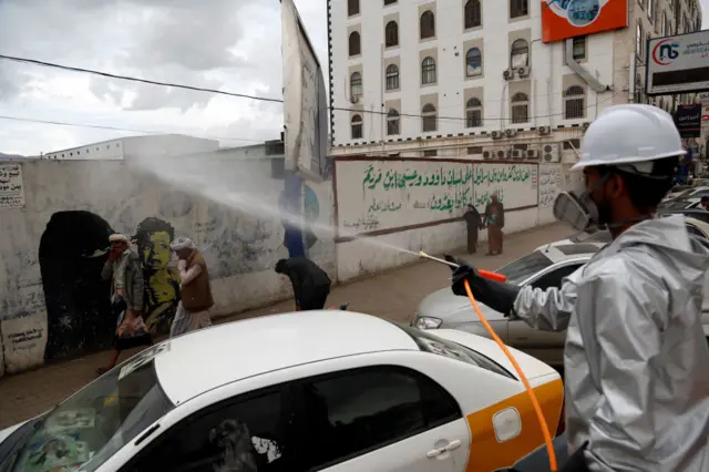 A health member wearing a protective uniform sprays disinfectants to help fight the spread of the coronavirus in Yemen