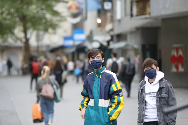 People wearing protective face masks walk on the main shopping street in Munich