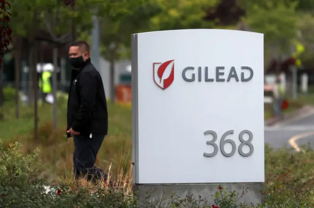 Man near a sign in front of the Gilead Sciences headquarters