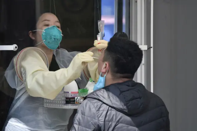 A medical staff member in a booth takes samples from a visitor for the COVID-19 coronavirus test