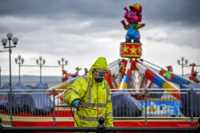 A cleaning worker sprays outside surfaces in Largs, Ayrshire on Saturday
