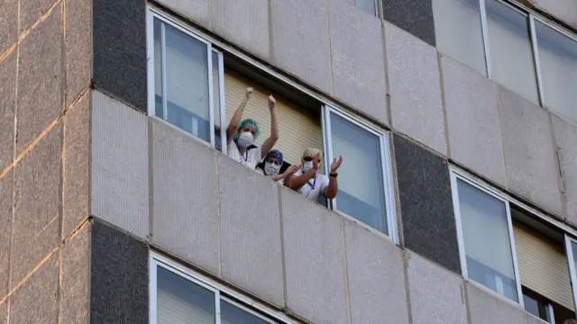 Healthcare workers in Madrid cheer from a window