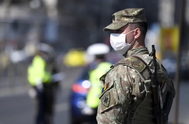 A soldier wearing a protective face masks watches the traffic in the Union Square in Bucharest, Romania