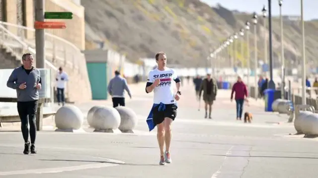 A runner runs along the seafront