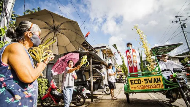 A priest in Borongan, in the Philippines, travels around town in a tricycle to bless people's palm fronds