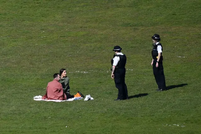 Police speak to a couple in London's Greenwich park on Sunday