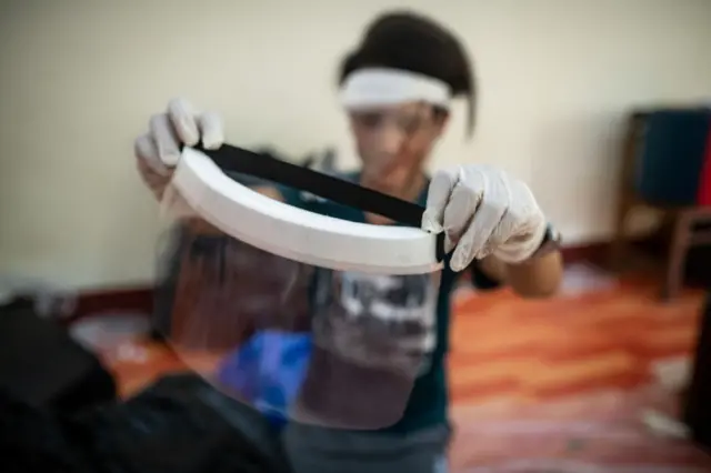 A medical student checks a handmade face shield before delivering them to doctors and nurses in Yangon, Myanmar