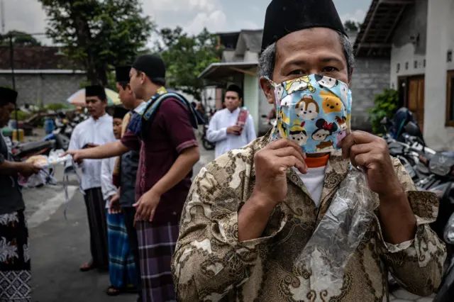 An Indonesian man wears a protective mask before entering a mosque as they attend Friday prayers