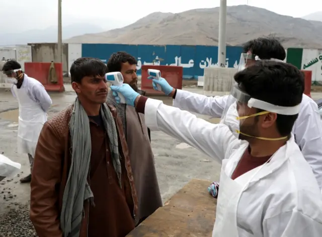 Medical officials in protective gear check the body temperature of travellers, who arrive from provinces, amid concerns about the spread of coronavirus disease (COVID-19), in Kabul, Afghanistan March 24, 2020.