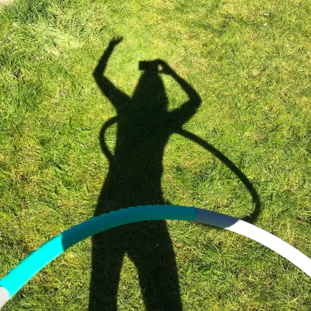 Person takes selfie of their shadow while hula-hooping