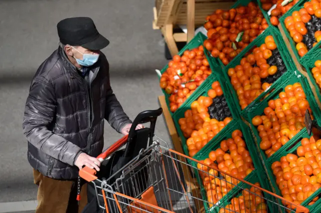 An Austrian man shops in a supermarket while wearing a mask