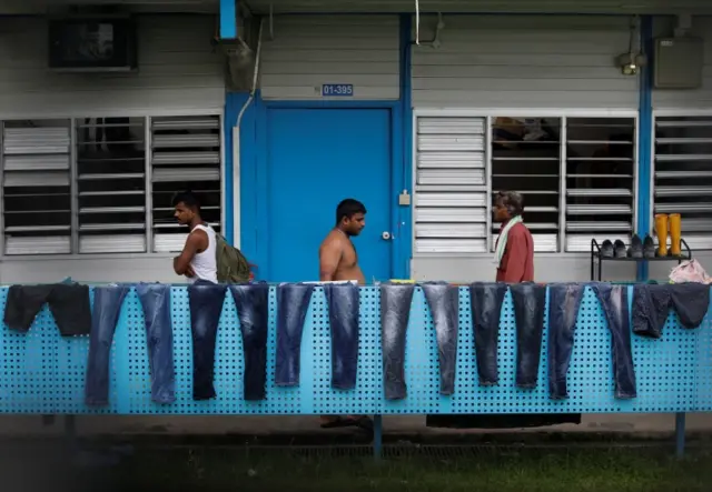 Workers pass a row of pairs of jeans hung to dry at Punggol S-11 workers" dormitory, which was gazetted to be an isolation facility after it became a cluster of coronavirus cases (COVID-19), in Singapore 6 April 2020. R