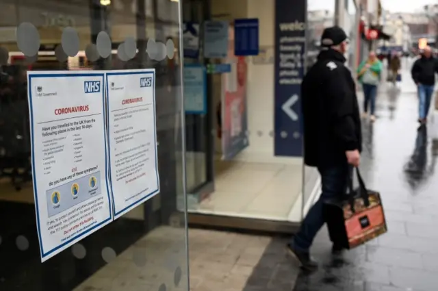 A coronavirus sign is seen in the window of a pharmacy in Liverpool, north west England on March 18, 2020.