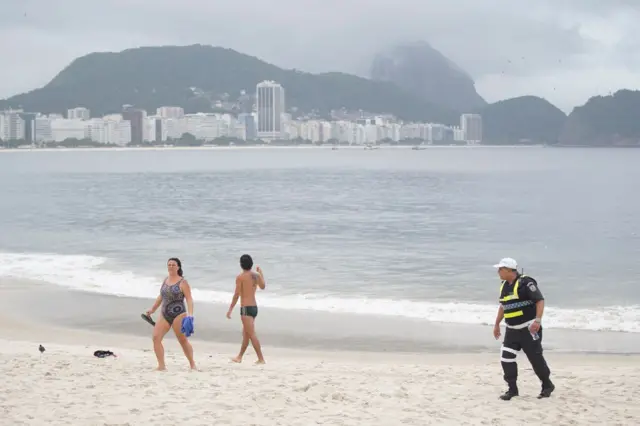 A Military policeman asks beachgoers to leave Copacabana beach during a lockdown