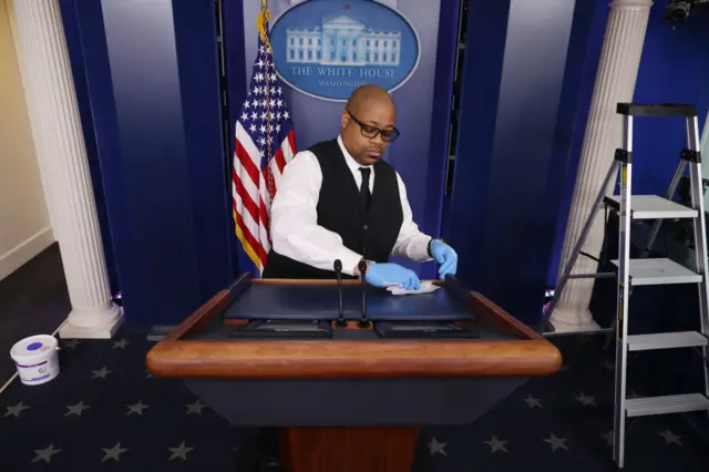 A cleaner wipes down the White House podium