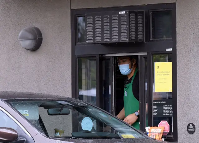 A Starbucks employee serves a walk-up customer amid the ongoing coronavirus pandemic on 7 April, 2020 in South Pasadena, California