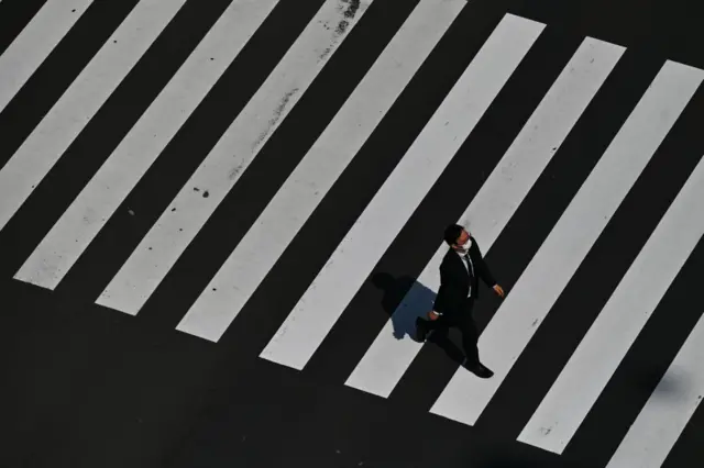 A man wearing a face mask crosses a street in Tokyo on April 8, 2020