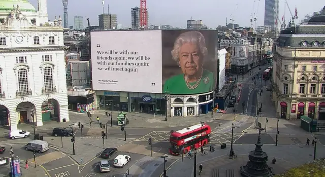 A billboard featuring a picture of and message from the Queen