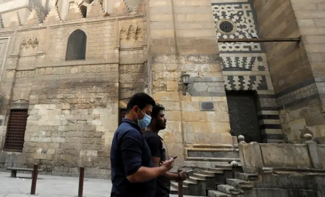 Two men walk past a mosque in Cairo, Egypt (6 April 2020)