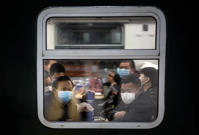 Passengers wearing face masks look out of the window of their train as it stops  in Wuhan