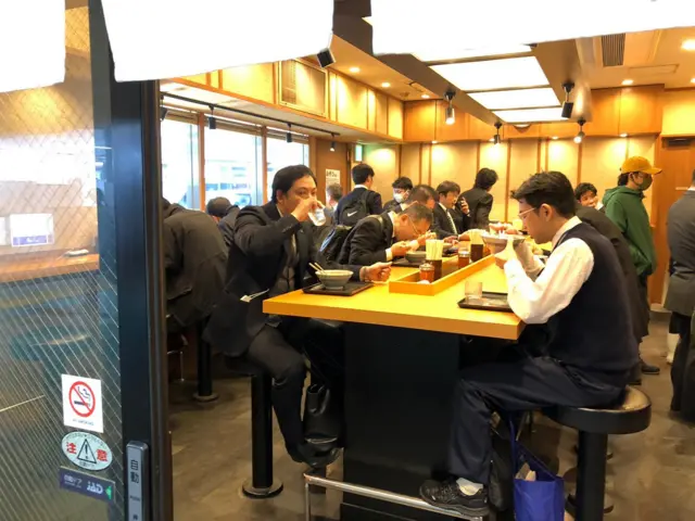 People eat breakfast in a busy Tokyo cafe