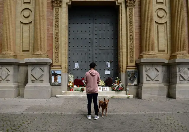 A man prays outside a church in Seville, Spain