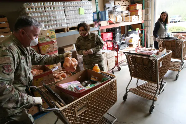 Colonel Gent Welsh and Staff Sergeant Amber Barker both from the Washington Air National Guard, and volunteer Vira Sayenko, help distribute food at the Nourish Pierce County food bank