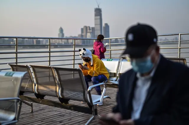 People wearing face masks ride a ferry to cross the Yangtze River in Wuhan in China"s central Hubei province on April 9, 2020