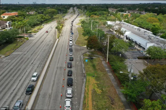 An aerial view from a drone shows vehicles lining up to receive food provided by the food bank Feeding South Florida on 6 April, 2020 in Sunrise, Florida