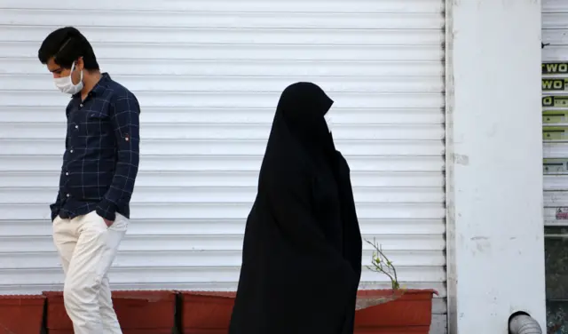 File photo showing a man and a woman wearing face masks walking in Tehran, Iran (5 April 2020)