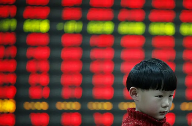 A child in front of a stock exchange electronic board in Huaibei, China