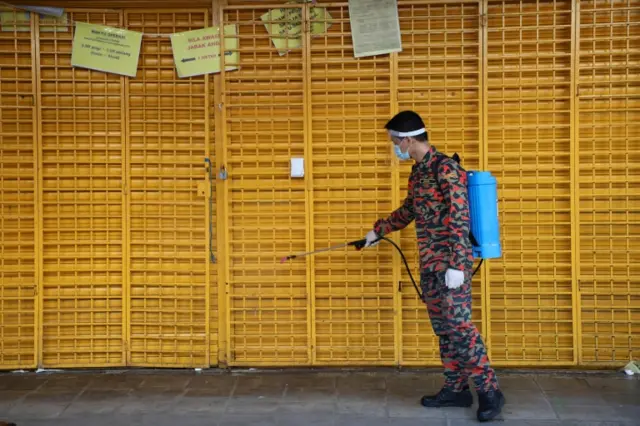 A firefighter disinfects a closed shop in Kuala Lumpur, Malaysia. Photo: 1 April 2020