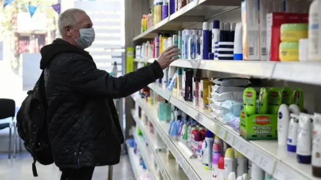 A man in a pharmacy, wearing a face mask