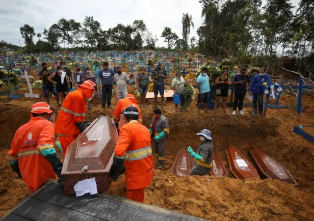 Gravediggers carry a coffin during a collective burial of people in Manaus