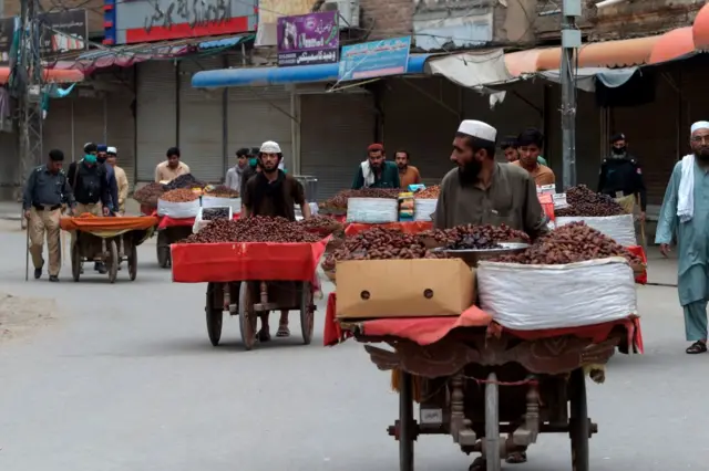 Policemen disperse vendors as time to close a market arrived during a government-imposed nationwide lockdown as a preventive measure against the COVID-19 coronavirus, along a street in Peshawar on April 28, 2020