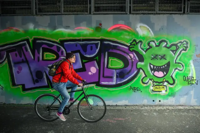 A young person cycles past some graffiti in Glasgow