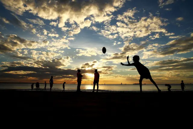 Boys playing football next to the water in Darwin