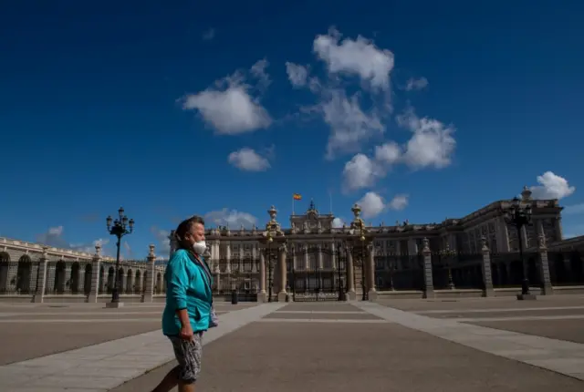 A woman walks in front of the Royal Palace in Madrid on May 10, 2020 during the hours allowed by the government to exercise