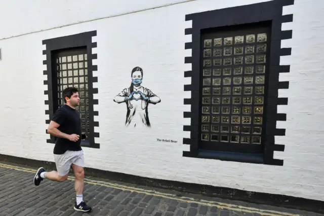 A runner goes past some graffiti on a wall in Glasgow's West End