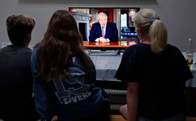 A family near London watch PM Boris Johnson address the nation