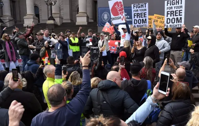 Anti-lockdown protesters chant on the steps of Victoria's state parliament in Melbourne