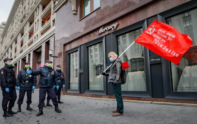 Policemen confront a Russian man holding a red flag near the Red Square in Moscow, Russia