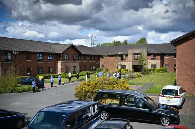 Staff and family stand beside a hearse carrying a former resident of Elderslie Care Home in Paisley prior to their funeral