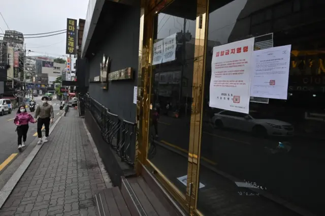 A couple wearing face masks walk past a night club, now closed, in the district of Itaewon in Seoul