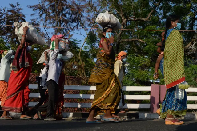 tranded migrant labourers walk carrying their belongings to board a special train from MGR Central railway station after the government eased a nationwide lockdown imposed as a preventive measure against the COVID-19 coronavirus, in Chennai on May 10, 2020